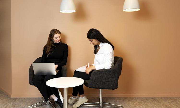 två studenter sitter och samtalar vid studieplatserna i pustervik