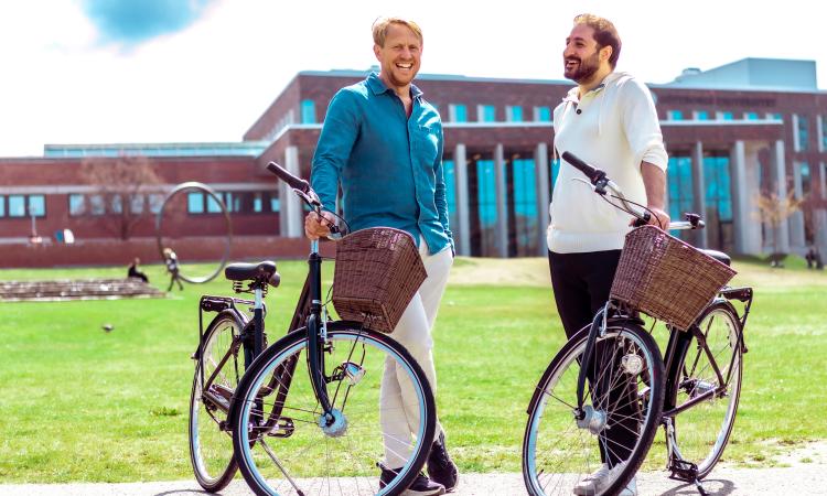 MOVS VD och kårordförande med varsin MOVS cykel framför Nya Humanisten