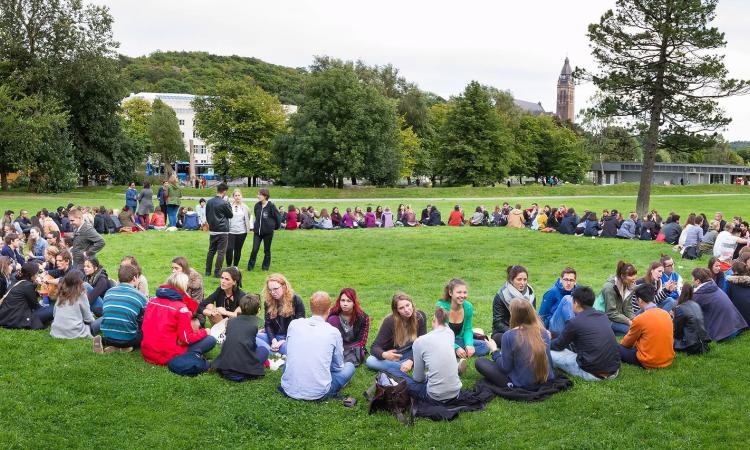 studenter sitter i en stor ring i slottskogen
